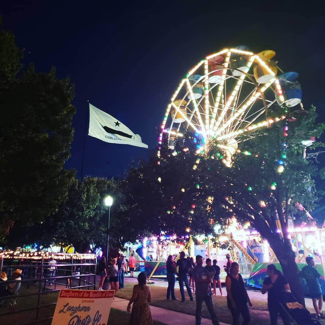 A night view of the carnival, the come and take it flag, and people enjoying the celebration