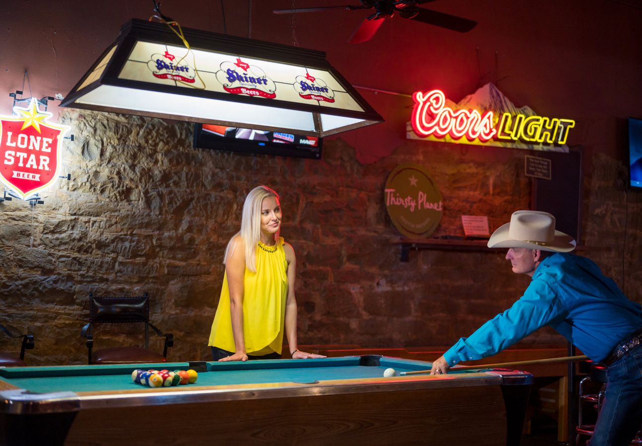 Showing a man and woman shooting pool.
